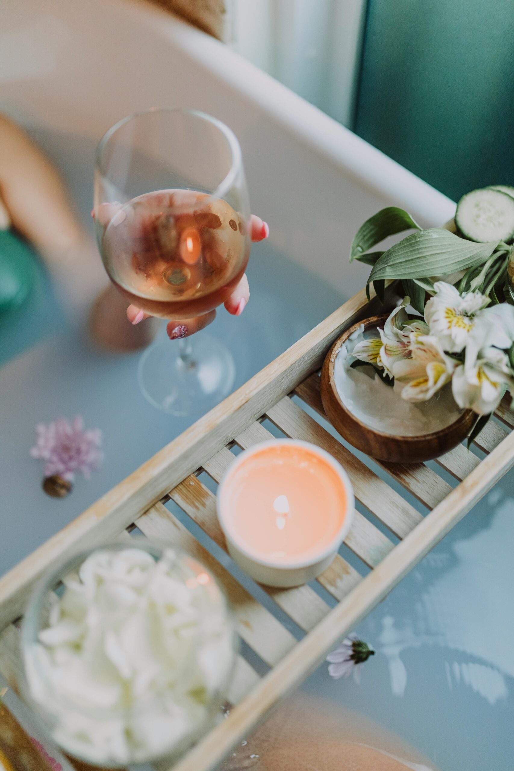 A serene bath setting with wine, candles, and flowers for a relaxing spa experience.